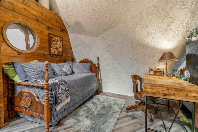 bedroom featuring wood-type flooring, a textured ceiling, and lofted ceiling