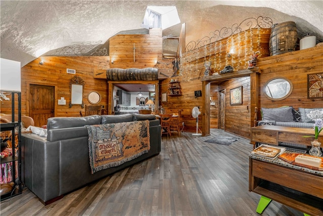 living room with dark hardwood / wood-style flooring, wood walls, lofted ceiling, and a textured ceiling