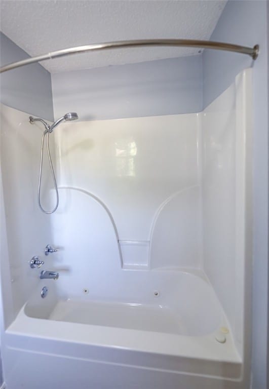 bathroom with a textured ceiling and washtub / shower combination