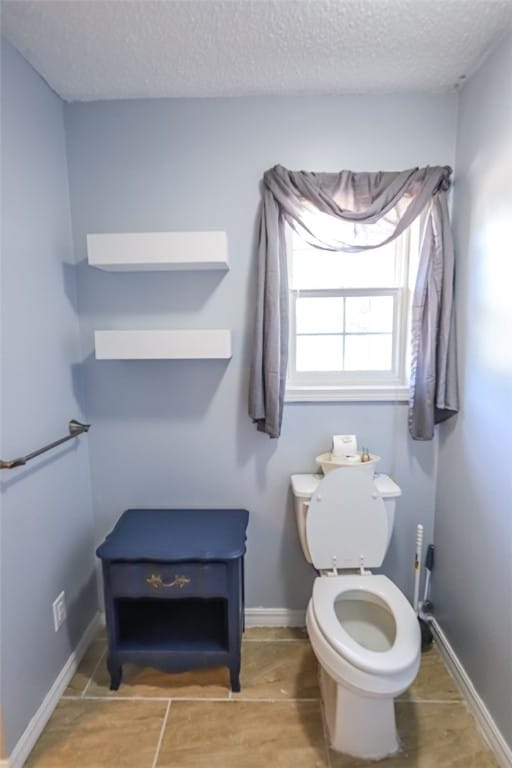 bathroom featuring a textured ceiling, tile patterned flooring, and toilet