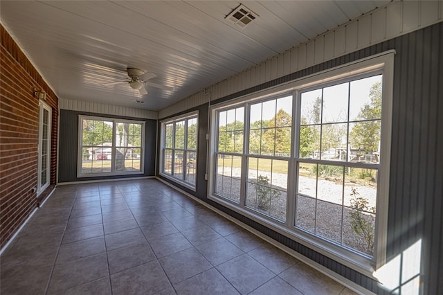 unfurnished sunroom featuring ceiling fan, wood ceiling, and a healthy amount of sunlight