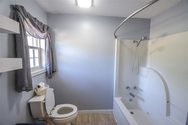 bathroom with a textured ceiling, shower / bath combination, wood-type flooring, and toilet