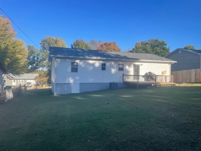 rear view of property featuring cooling unit, a lawn, and a deck