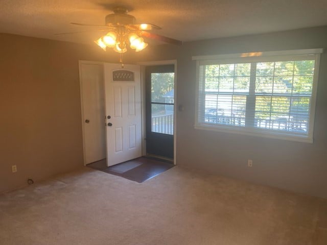 doorway to outside with ceiling fan and carpet flooring