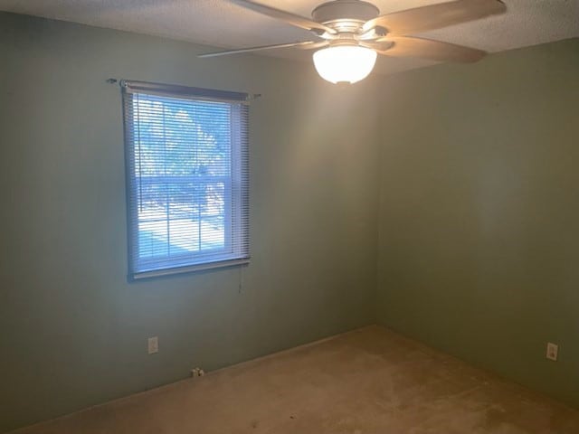 carpeted empty room featuring a textured ceiling and ceiling fan