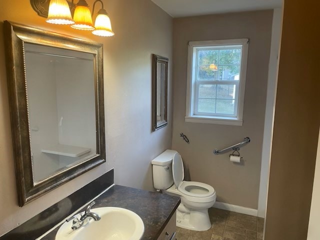 bathroom featuring toilet, a notable chandelier, vanity, and baseboards