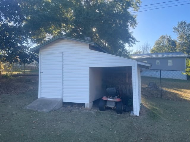 view of outdoor structure with a garage, an outbuilding, and fence