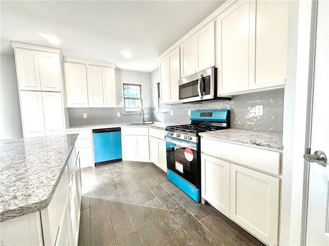 kitchen featuring light stone countertops, appliances with stainless steel finishes, decorative backsplash, sink, and white cabinetry