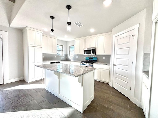 kitchen featuring hanging light fixtures, a center island, white cabinets, and stainless steel appliances