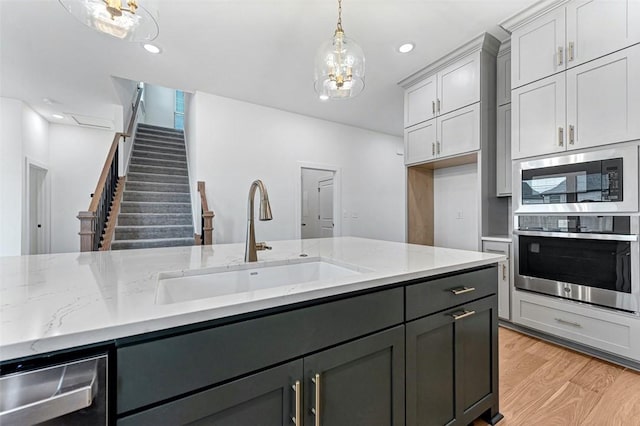 kitchen featuring stainless steel appliances, sink, light stone counters, and gray cabinets