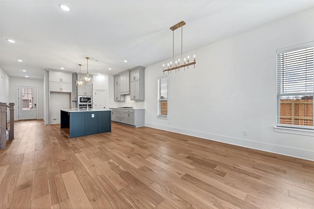 kitchen featuring pendant lighting, an island with sink, light hardwood / wood-style flooring, and a wealth of natural light