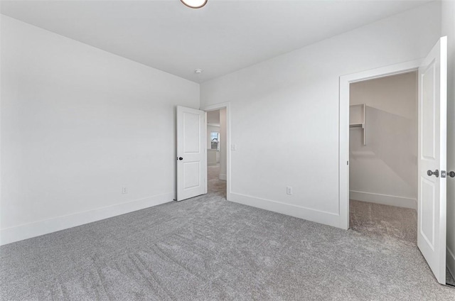 unfurnished bedroom with a spacious closet and carpet floors