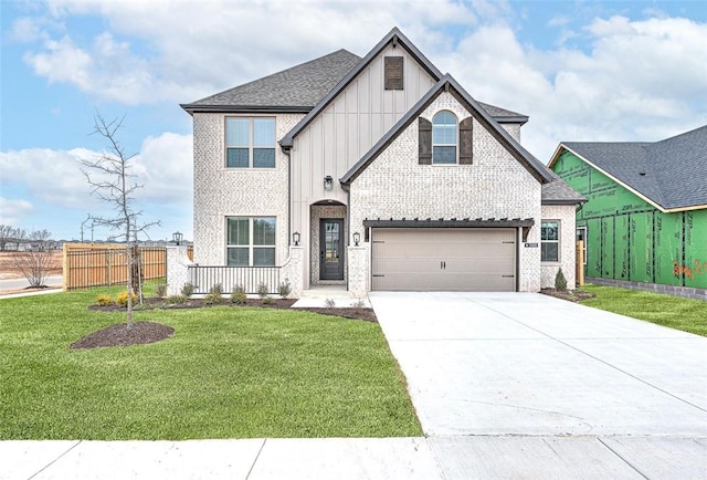 view of front of house with fence, driveway, an attached garage, a front lawn, and brick siding