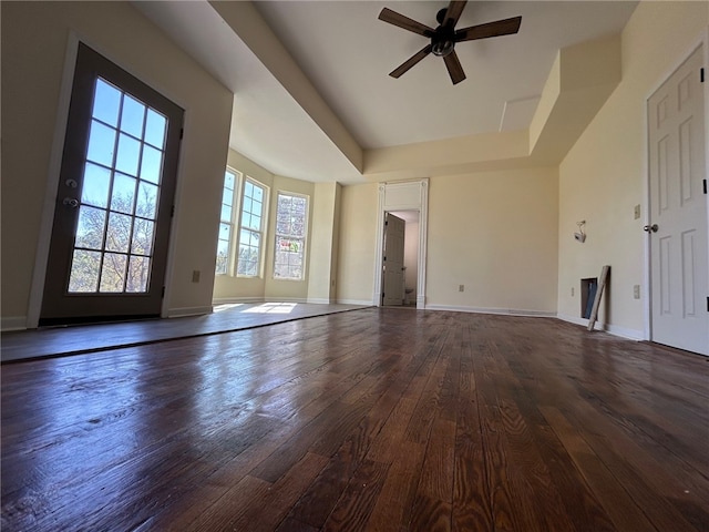 unfurnished living room featuring ceiling fan, a raised ceiling, and dark hardwood / wood-style floors