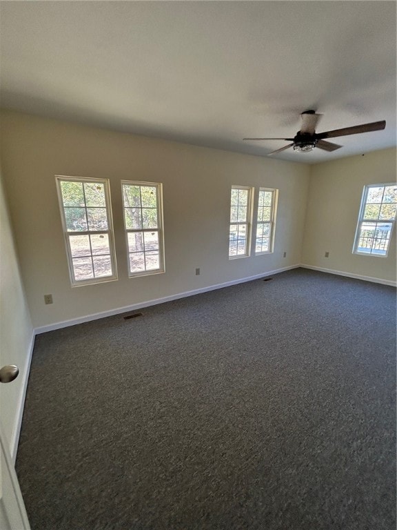 carpeted spare room featuring ceiling fan and a wealth of natural light