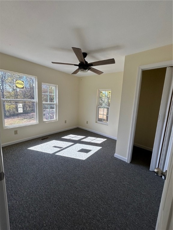 carpeted spare room featuring ceiling fan and a wealth of natural light