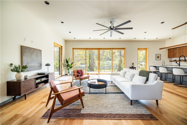 living room featuring light hardwood / wood-style floors, ceiling fan, and sink