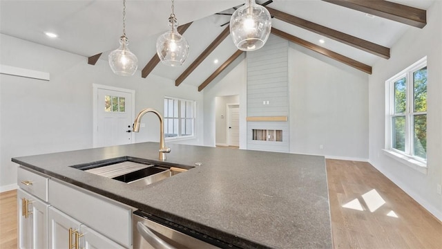 kitchen with decorative light fixtures, white cabinetry, light hardwood / wood-style floors, sink, and lofted ceiling with beams