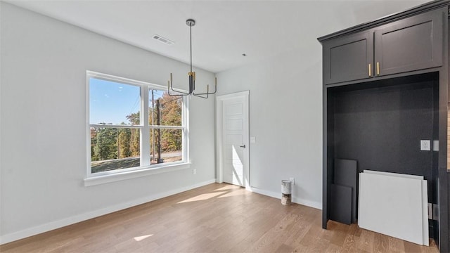 unfurnished dining area with a chandelier and wood-type flooring