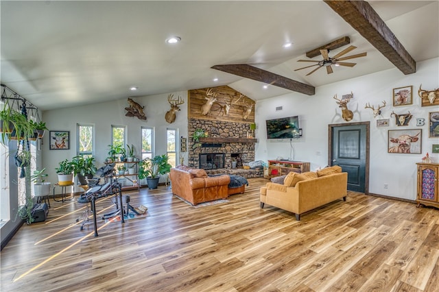 living room featuring lofted ceiling with beams, a stone fireplace, ceiling fan, and light hardwood / wood-style flooring