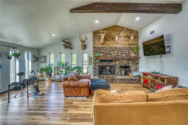 living room with hardwood / wood-style flooring, a stone fireplace, and lofted ceiling