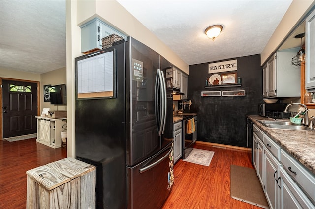 kitchen featuring sink, black appliances, dark hardwood / wood-style floors, and a textured ceiling