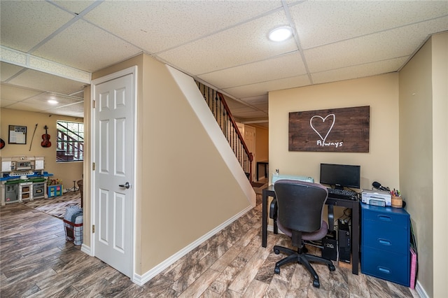 home office with a drop ceiling and hardwood / wood-style flooring