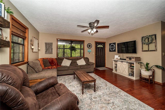 living room with dark wood-type flooring, ceiling fan, and a textured ceiling