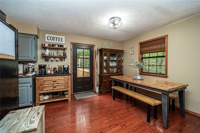 dining space with dark wood-type flooring, a textured ceiling, and a wealth of natural light