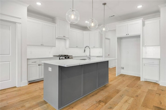 kitchen with a center island with sink, white cabinetry, and light hardwood / wood-style flooring