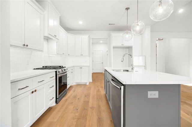 kitchen with white cabinets, sink, stainless steel appliances, and a center island with sink