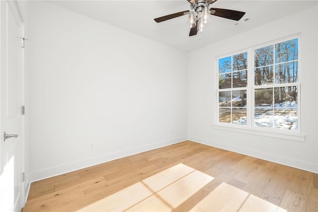 spare room with ceiling fan, plenty of natural light, and wood-type flooring