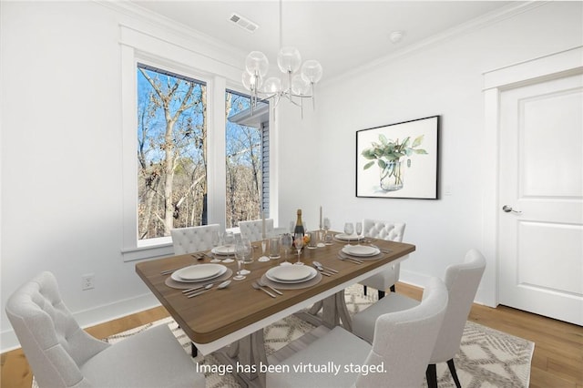 dining room with crown molding, a chandelier, and light hardwood / wood-style floors