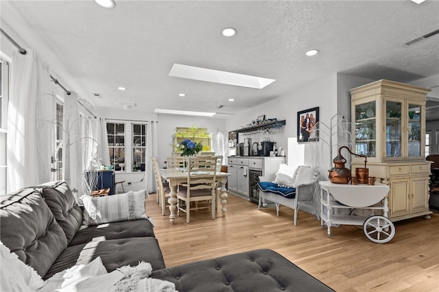 living room featuring a skylight, a textured ceiling, and light wood-type flooring