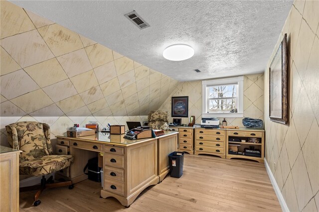 office space with lofted ceiling, a textured ceiling, and light hardwood / wood-style floors