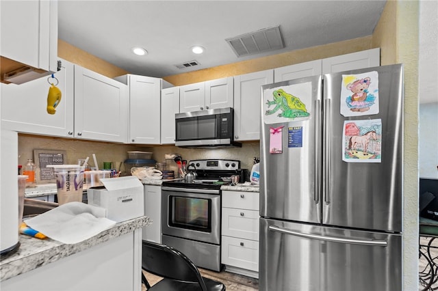 kitchen with white cabinetry, light stone countertops, appliances with stainless steel finishes, and light hardwood / wood-style flooring