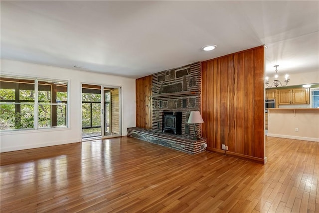 unfurnished living room featuring baseboards, an inviting chandelier, and light wood-style floors