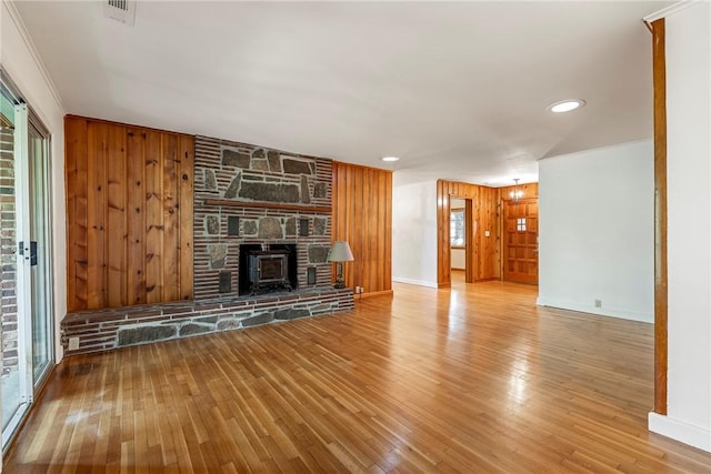 unfurnished living room with wooden walls, wood finished floors, visible vents, and a healthy amount of sunlight