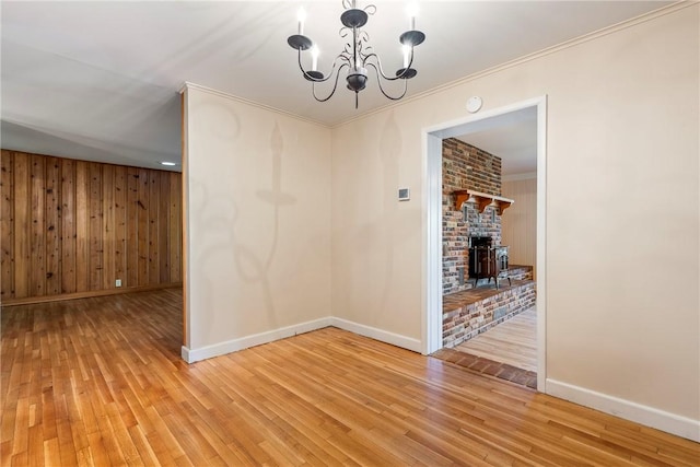 unfurnished dining area with baseboards, wood walls, an inviting chandelier, and light wood-style floors