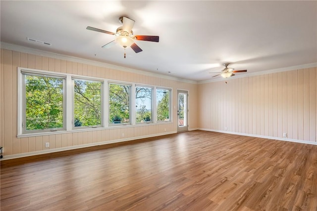 spare room featuring plenty of natural light, wood finished floors, visible vents, and a ceiling fan