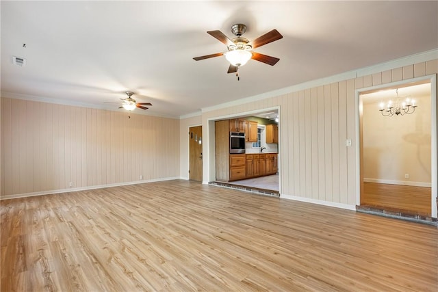 unfurnished living room with ornamental molding, light wood-style flooring, baseboards, and ceiling fan with notable chandelier