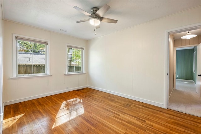 unfurnished room featuring baseboards, wood finished floors, visible vents, and a ceiling fan