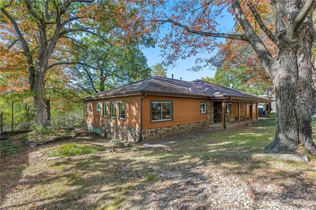 view of side of property with stone siding and a lawn