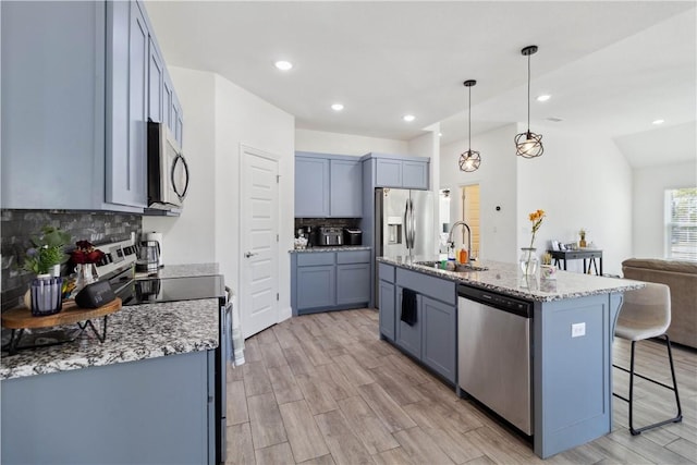kitchen with light stone countertops, a sink, a kitchen breakfast bar, tasteful backsplash, and appliances with stainless steel finishes