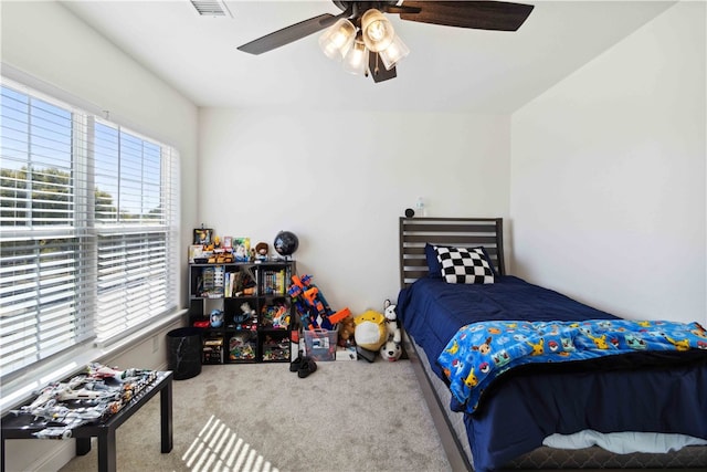 carpeted bedroom featuring ceiling fan and multiple windows