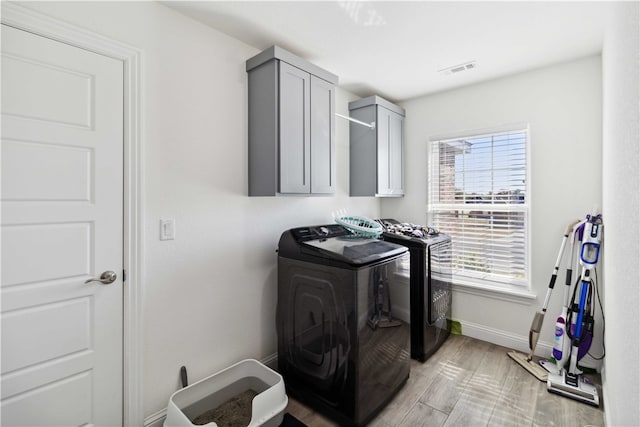 washroom featuring washer and dryer, light hardwood / wood-style floors, and cabinets