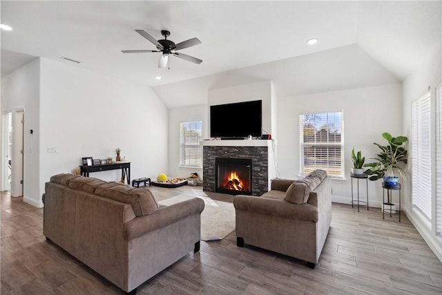 living room featuring visible vents, a healthy amount of sunlight, a stone fireplace, and lofted ceiling