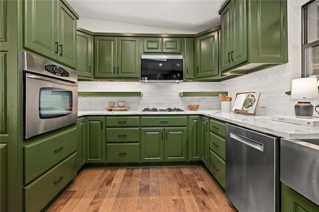 kitchen with light hardwood / wood-style floors, stainless steel appliances, vaulted ceiling, and green cabinetry