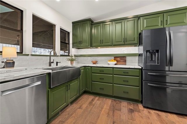 kitchen with decorative backsplash, hardwood / wood-style floors, appliances with stainless steel finishes, sink, and green cabinetry