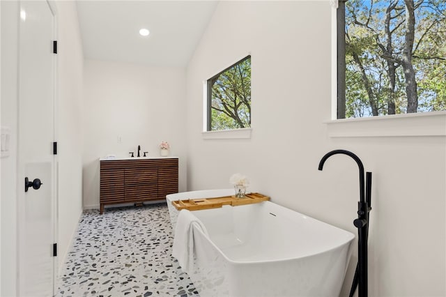 bathroom featuring vanity, lofted ceiling, and a bathing tub